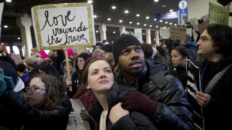 Leigh Wilson and Nate Hall protest President Donald Trump's executive order on immigration at Philadelphia International Airport. Wilson says it is the fourth anti-trump protest she has attended. (Branden Eastwood for WHYY)