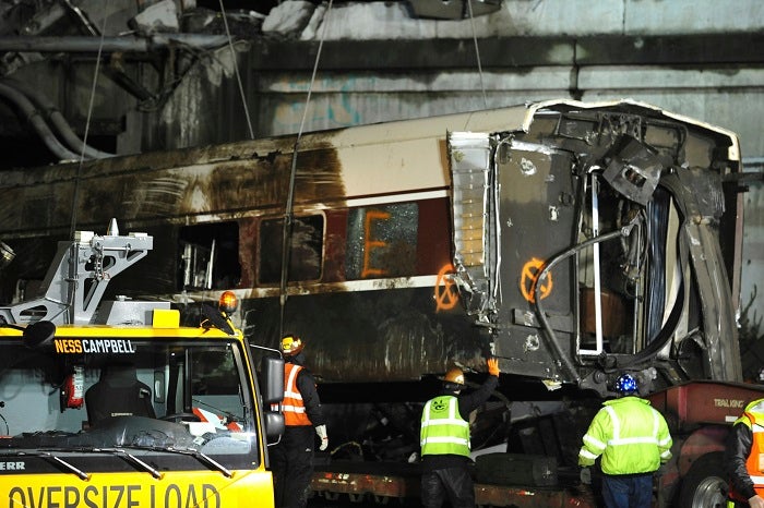 A damaged Amtrak passenger train car is lifted from the tracks at the site of the derailment of an Amtrak train in Dupont, Wash., Tuesday, Dec. 19, 2017. Investigators are looking into whether the Amtrak engineer whose speeding train plunged off an overpass on Monday, killing several people, was distracted by the presence of an employee-in-training next to him in the locomotive, a federal official said Tuesday. (Thomas James/Pool via AP)