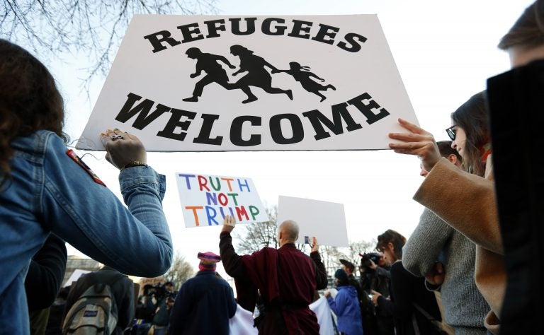 Protesters hold signs near the White House during a protest about President Trump's immigration policies. A proposed presidential action would freeze immigration from mostly Muslim countries.
(Alex Brandon/AP)