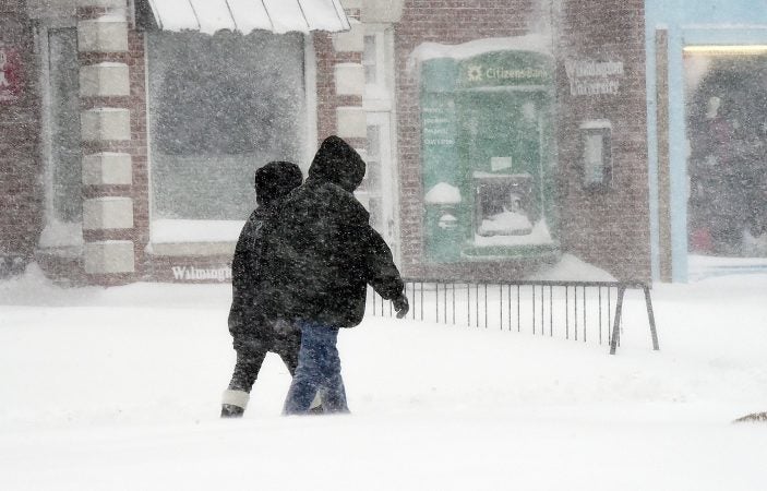 A few people ventured out to walk amid the blowing and drifting snow in Rehoboth Beach. (Chuck Snyder/for WHYY)