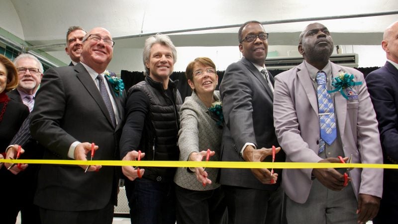 Sister Mary Scullion (center) of Project Home flanked by rocker philanthropist Jon Bon Jovi and City Councilman Darrell Clarke, helps cut the ribbon to open the Hub of Hope, a refuge for homeless people in the Center City subway concourse. (Emma Lee/WHYY)