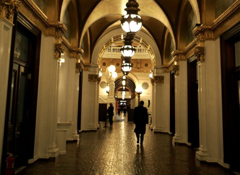 A man walks down a hall toward the light of the Capitol rotunda, in Harrisburg, Pa.