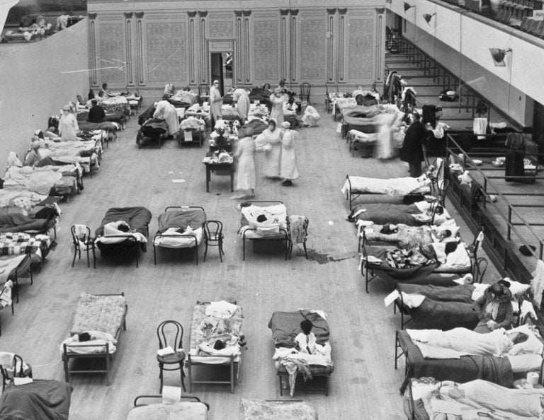 In this 1918 photo made available by the Library of Congress, volunteer nurses from the American Red Cross tend to influenza patients in the Oakland Municipal Auditorium, used as a temporary hospital. (Edward A. 