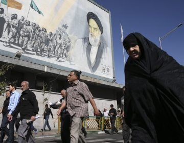 Iranian worshippers walk past a painting of the late revolutionary founder Ayatollah Khomeini and Basij paramilitary force members, at the conclusion of a Friday prayer ceremony in Tehran, Iran, Friday, Oct. 13, 2017. (Vahid Salemi/AP Photo)