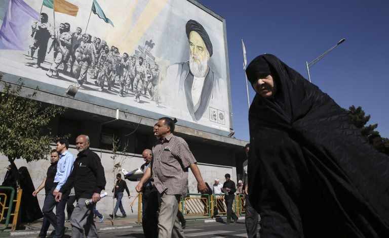 Iranian worshippers walk past a painting of the late revolutionary founder Ayatollah Khomeini and Basij paramilitary force members, at the conclusion of a Friday prayer ceremony in Tehran, Iran, Friday, Oct. 13, 2017. (Vahid Salemi/AP Photo)