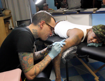 Eagles fans receive free Eagles tattoos Wednesday morning at Moo Tattoo on South Street. (Kimberly Paynter/WHYY)