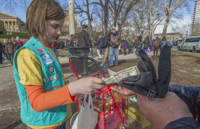 Adah Di'Alba sells Girl Scout Cookies at the base of the Art Museum. Di'Alba was attending the march with her mother Ginna Di'Alba, and grandmother Andrea Cauble, both former Girl Scouts. (Jonathan Wilson for WHYY)