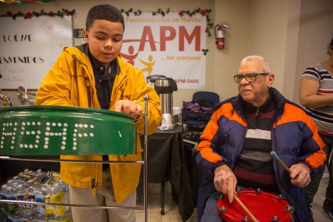 Asaf Barrios, 11, jams out on his steele drum accompanied by his father, Raul, at APM's Three Kings Day/Octavious celebration for displaced families from Puerto Rico in North Philadelphia on January 12 2018. (Emily Cohen for WHYY)