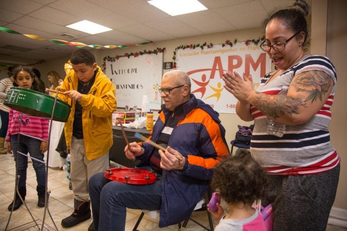 Asaf Barrios, 11, jams out on his steele drum accompanied by his father, Raul, at APM's Three Kings Day/Octavious celebration for displaced families from Puerto Rico in North Philadelphia on January 12 2018. (Emily Cohen for WHYY)