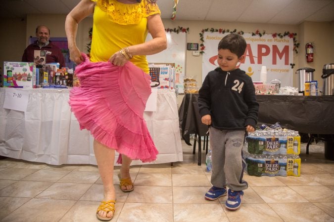 5 year old Jose Marlon learns how to dance a traditional dance from Puerto Rico at APM's Three Kings Day/Octavious celebration for diplaced families from Puerto Rico in North Philadelphia on January 12 2018. (Emily Cohen for WHYY)