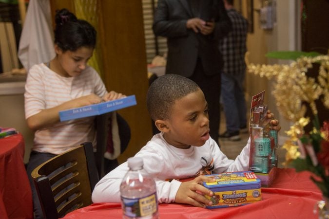 Children take a closer look at their new toys at APM's Three Kings Day/Octavious celebration for diplaced families from Puerto Rico in North Philadelphia on January 12 2018. (Emily Cohen for WHYY)