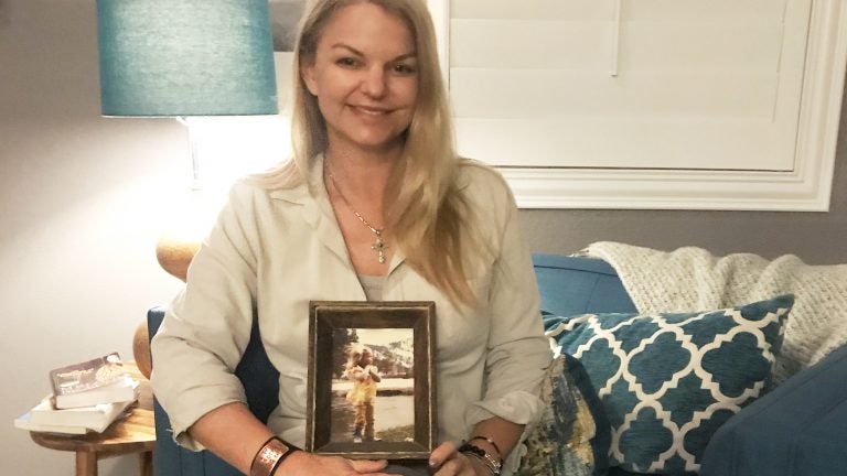 Christine Caria in her home, holding a picture of her as a child in Lake Tahoe. It's her 