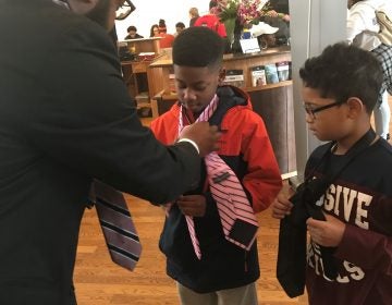 William Merritt Jr. teaches boys how to fix a tie during MLK Day of Service event. (Nichelle Polston/WHYY)