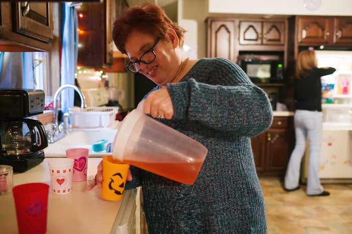 Pauline helps pour juice for dinner at her group home.