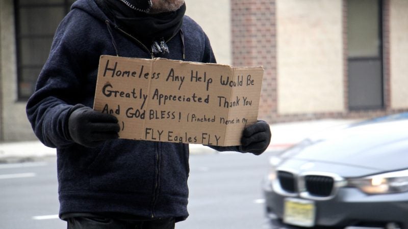 A homeless includes a plug for the Eagles on his sign as he works the corner of 5th and Callowhill streets
. (Emma Lee/WHYY)