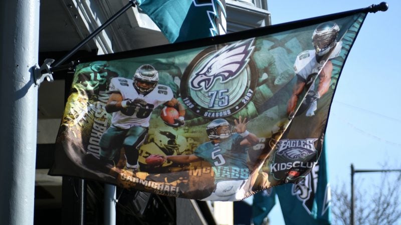 Flags in support of the Philadelphia Eagles hang above a bar in Manayunk on Wednesday. The banner harkens back to the Eagles 75th anniversary season in 2007, when the team compiled an 8–8 record and a last-place finish in the NFC East. (Bastiaan Slabbers for WHYY)