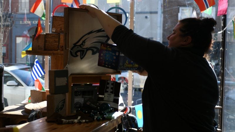 Meredith Podob arranges handmade eagles items on the counter of her gift shop, in Manayunk, on Wednesday. (Bastiaan Slabbers for WHYY)