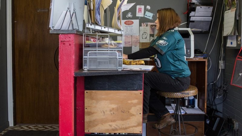 Colleen McClure, 41, completes some front office work while showing off her Eagles pride at Girls Auto Shop in Upper Darby. (Emily Cohen for WHYY)