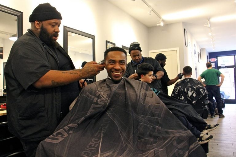 Male barber giving customer a haircut in barbershop - Stock Image