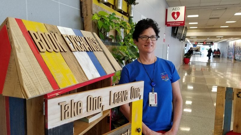 Leah Douglas, curator at the Philadelphia International Airport, stocks the book trade she designed with books left behind in airplanes. (Peter Crimmins/WHYY)