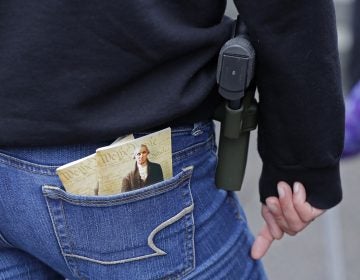 In this Jan. 12, 2018 photo, a woman wears a gun in a holster next to two copies of the U.S. Constitution during a gun rights rally at the Capitol in Olympia, Wash.