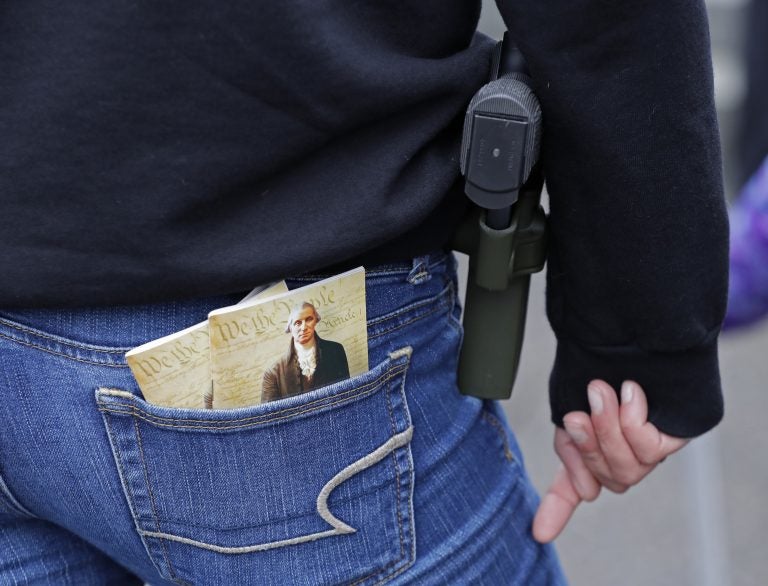 In this Jan. 12, 2018 photo, a woman wears a gun in a holster next to two copies of the U.S. Constitution during a gun rights rally at the Capitol in Olympia, Wash.