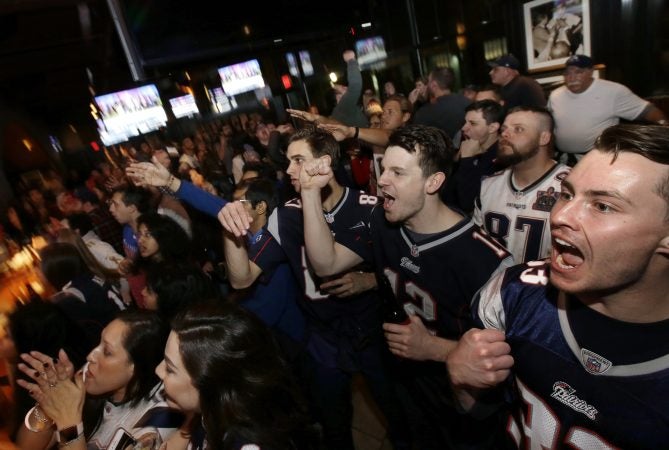 Coleman Hands, center, of Dallas, Davis Smith, second from right, of Austin, Texas, and Brian Moran, right, of Boston cheer while watching the first half of the NFL Super Bowl 52 football game between the New England Patriots and the Philadelphia Eagles in Minneapolis, Sunday, Feb. 4, 2018. (AP Photo/Steven Senne)