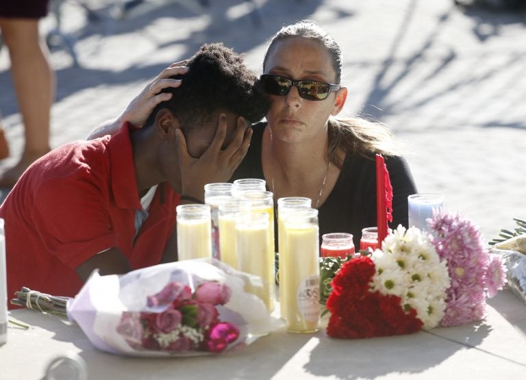 Pamela Tilton, (right), comforts Che James-Riley, 18, as they light a candle at a memorial for the victims of the shooting at Marjory Stoneman Douglas High School, Thursday, Feb. 15, 2018, in Parkland, Fla. (Wilfredo Lee/AP Photo)
