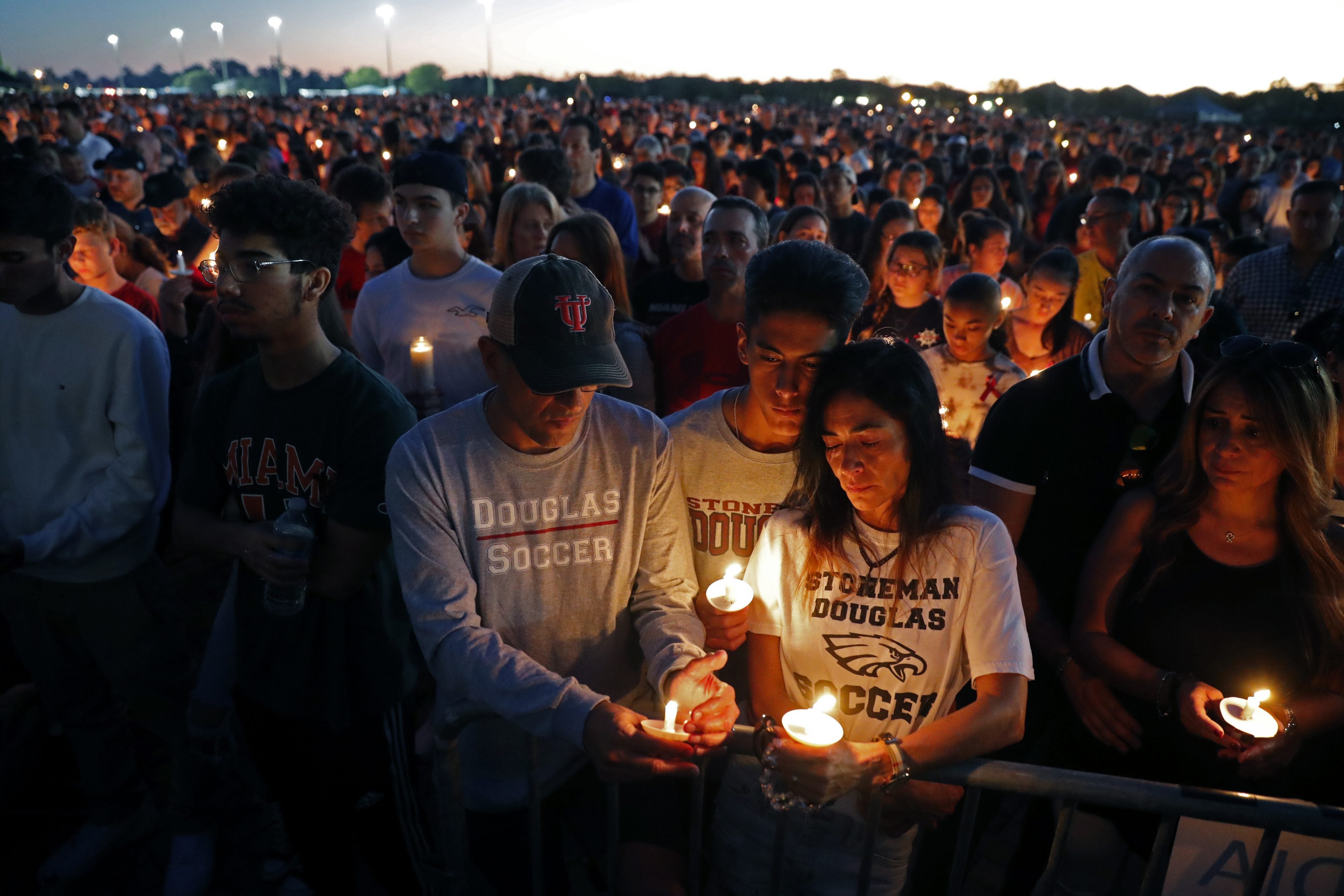 Jorge Zapata, Jr., center, a student at Marjory Stoneman Douglas High School, holds candles with his mother Lavinia Zapata, and father Jorge Zapata, Sr., during a candlelight vigil for the victims of the Wednesday shooting at the school, in Parkland, Fla., Thursd