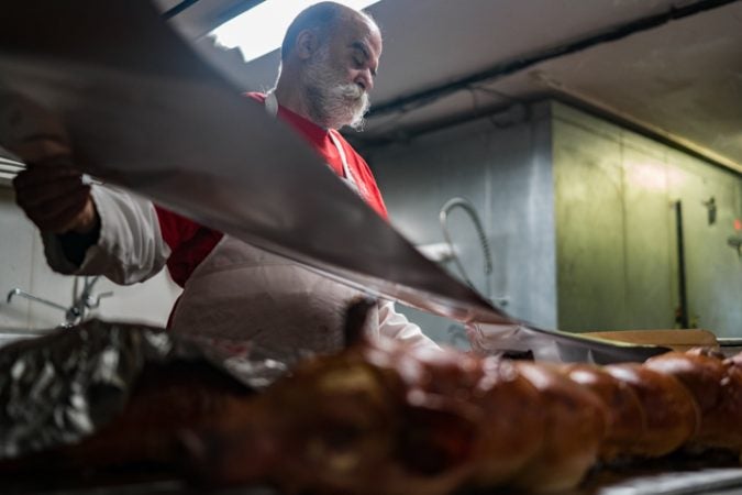 Sid Dk pulls tin foil for packaging at Esposito’s Porchetta in South Philadelphia before the Super Bowl on January 4, 2018. (Branden Eastwood for WHYY)