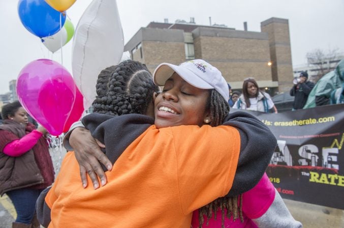 Mothers Bonded by Grief member Johndell Gredic, left, embraces Erase the Rate founder Davida Garner in the parking lot of the Philadelphia Medical Examiner’s office. (Jonathan Wilson for WHYY