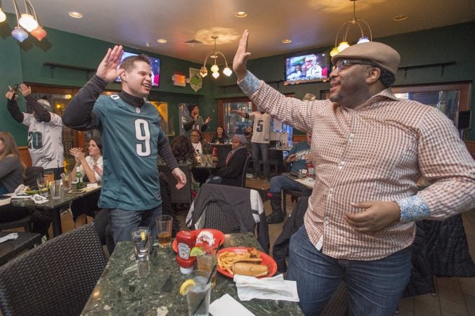 Eric Yoder, left, and Raymond Jones high five at Jon's Bar & Grille as Eagles score a touchdown.