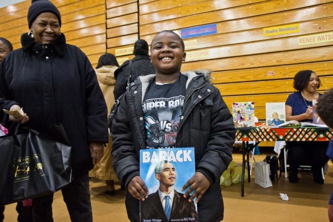 Semaj Scott, 7, likes books about history and sports. His grandmother, Juanita Scott looks on at the 26th annual African-American Children’s Book Fair at the Community College of Philadelphia. (Kimberly Paynter/WHYY)