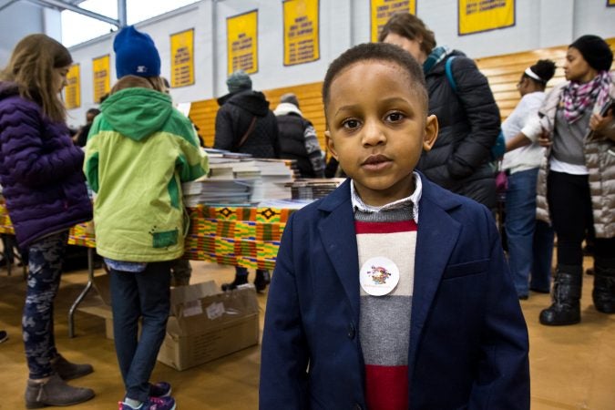 Ellis McGruder Jr., 4, and his dad attended the 26th annual African-American Children’s Book Fair at the Community College of Philadelphia. They are starting a YouTube channel to post videos of them reading together. (Kimberly Paynter/WHYY)
