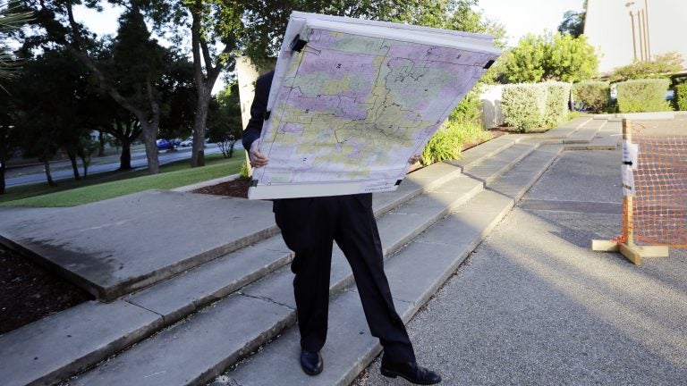 A man with a set of maps heads to a federal courthouse in San Antonio last year for a redistricting trial. Texas is one of three states with cases before the Supreme Court in redistricting. (Eric Gay/AP)
