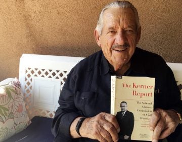 Former Democratic Sen. Fred Harris of Oklahoma, seen in August 2017, holds a copy of The Kerner Report, as he discusses its 50th anniversary. Harris is the last surviving member of the Kerner Commission.
(Russell Contreras/AP)