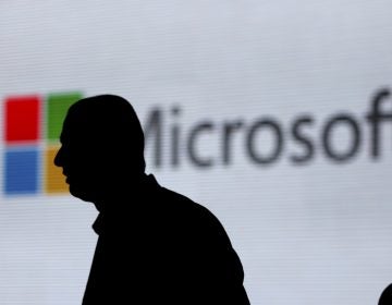 An unidentified man walks in front of the Microsoft logo at an event in New Delhi, India. Microsoft is at the center of a Supreme Court case on whether it has to turn over emails stored overseas. (Altaf Qadri/AP)