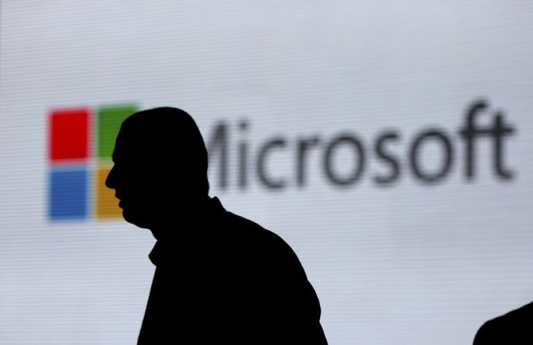An unidentified man walks in front of the Microsoft logo at an event in New Delhi, India. Microsoft is at the center of a Supreme Court case on whether it has to turn over emails stored overseas. (Altaf Qadri/AP)