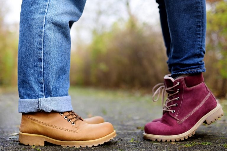 Closeup photo of male and female legs during a date in autumn park. Love couple romantic concept