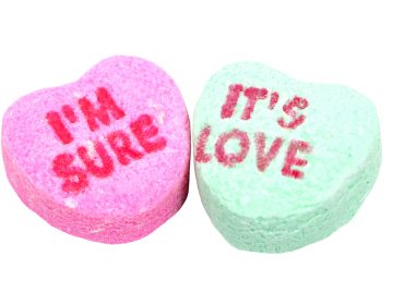two candy hearts traditionally given around valentine's day with the message i'm sure it's love