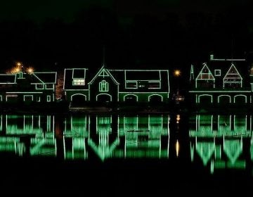 Houses on Boathouse row are lit up with green lights at night.