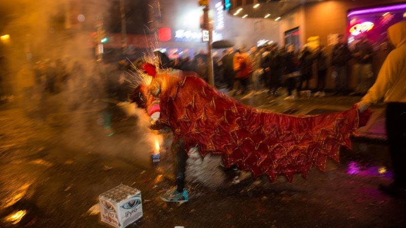 A member of the Philly Suns does a lion dance through firecrackers as they go off in celebration of the Chinese New Year in Phildelphia's Chinatown on February 15, 2018. (Emily Cohen for WHYY)