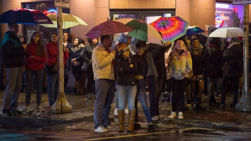 Dan Fogarty (center) and his wife Trish, stand and joke with family friend Angel Rodriguez, 20, as they wait for the lion dances to begin in celebration of the Chinese New Year in Phildelphia's Chinatown on February 15, 2018. (Emily Cohen for WHYY)