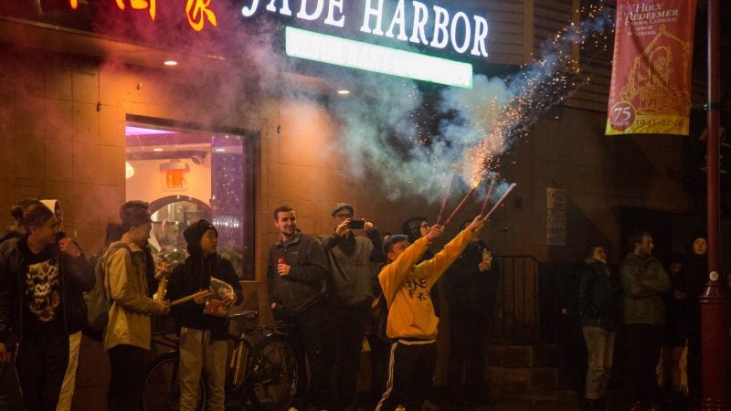 Matt Hing, 15, (center) lights off 4 firecrackers at once in celebration of the the Chinese New Year in Phildelphia's Chinatown on February 15, 2018. (Emily Cohen for WHYY)