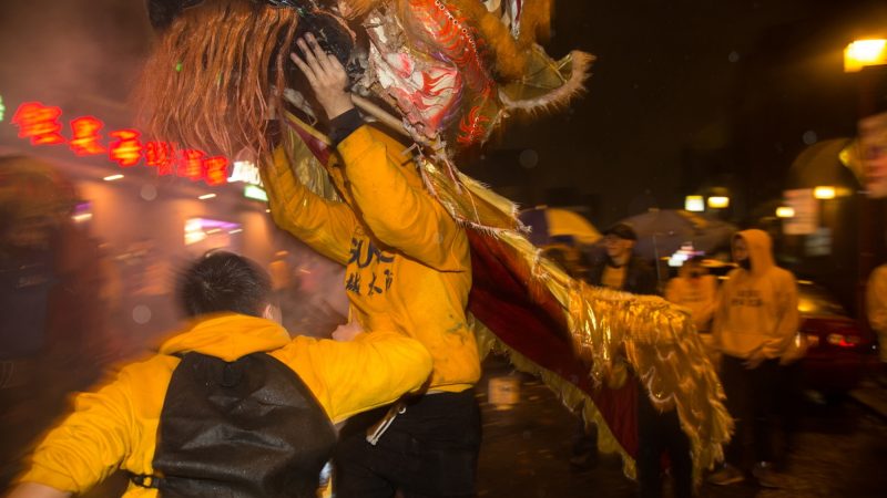 A friend says hi to a dancer during his turn as the lion's head during the Midnight Lion Dance to celebrate the Chinese New Year in Phildelphia's Chinatown on February 15, 2018. (Emily Cohen for WHYY)