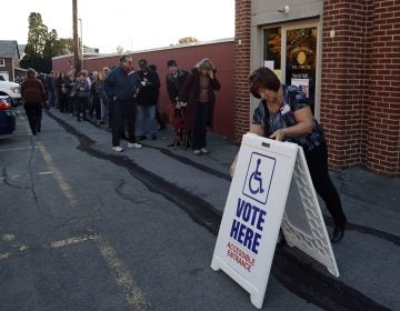 An election official places a sign as voters line up outside a polling place November 2016 in Fogelsville, Pa. (AP Photo/Matt Slocum)