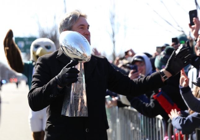 Doug Pederson high fives fans with the Vince Lombardi trophy on Broad Street during the Philadelphia Eagles Super Bowl Championship parade on Feb. 8, 2018.
