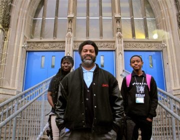 Mastery Shoemaker Principal Sharif El-Mekki, 46. stamds at the entrance to the school with students Essi Gasonu (left) and Bryce Thompson.  (Emma Lee/WHYY)