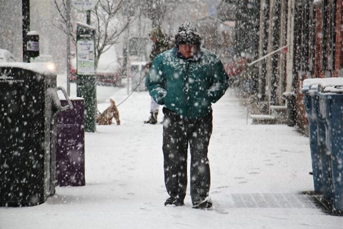Pedestrians in Old City are coated in snow. (Emma Lee/WHYY)