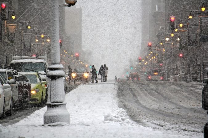 Snow falls fast and thick on South Broad Street near City Hall. (Emma Lee/WHYY)